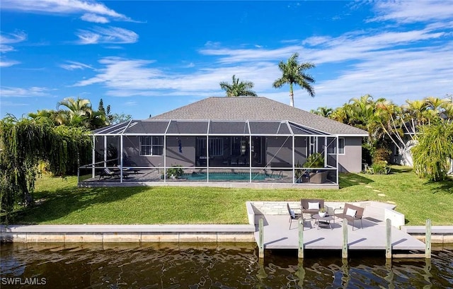 rear view of house with glass enclosure, a water view, stucco siding, and a yard