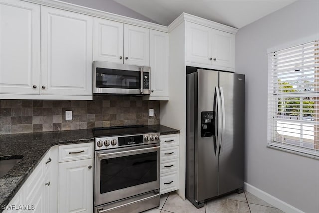 kitchen featuring white cabinets, baseboards, stainless steel appliances, dark stone counters, and tasteful backsplash