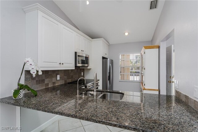 kitchen with visible vents, a peninsula, dark stone countertops, and stainless steel appliances