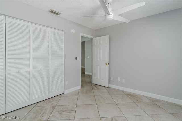 unfurnished bedroom with baseboards, a textured ceiling, light tile patterned flooring, visible vents, and a closet