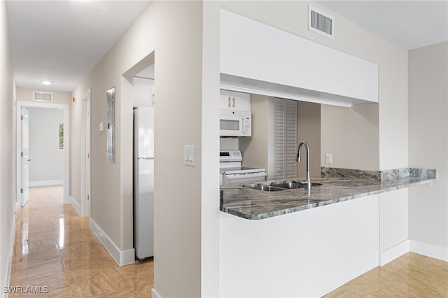 kitchen with a sink, visible vents, stone counters, and white appliances