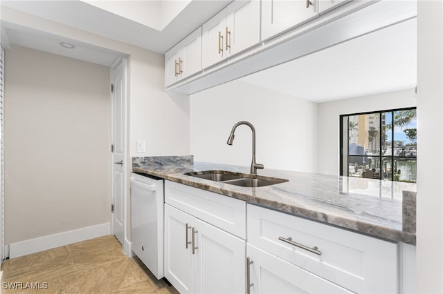 kitchen with white cabinetry, a sink, light stone counters, and dishwasher