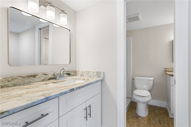 bathroom featuring baseboards, visible vents, toilet, and vanity