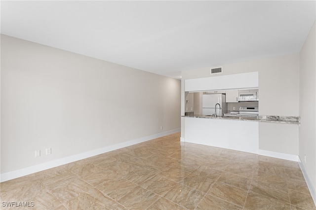 unfurnished living room with baseboards and visible vents