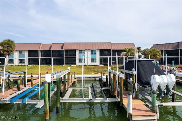 dock area featuring a water view, boat lift, and a yard