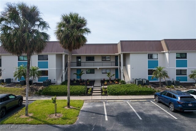 view of property featuring uncovered parking, stairway, and central AC
