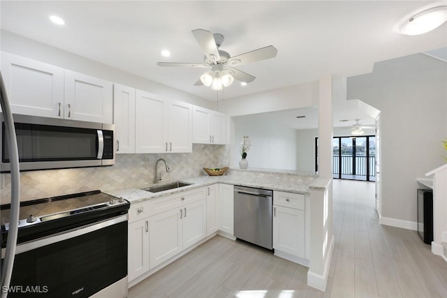 kitchen featuring light stone counters, backsplash, a sink, stainless steel appliances, and ceiling fan