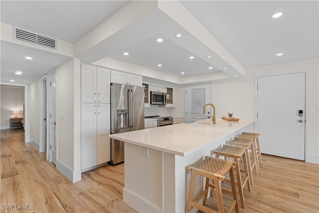222 Harbour Dr Unit 104, Naples, FL 34103 - kitchen featuring visible vents, a breakfast bar, stainless steel appliances, a sink, and light wood-type flooring