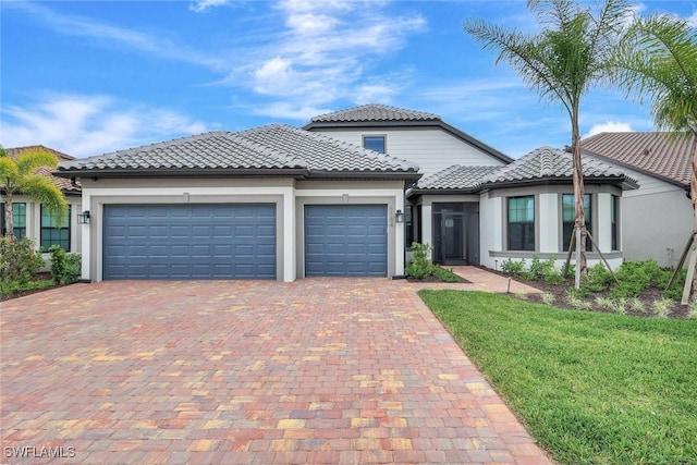 mediterranean / spanish home with a tile roof, stucco siding, a garage, and driveway