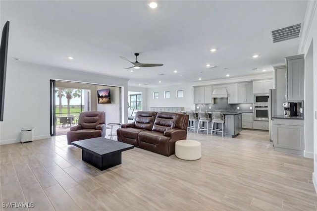 living room featuring visible vents, baseboards, recessed lighting, a ceiling fan, and light wood-type flooring