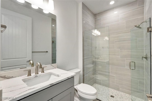 bathroom featuring vanity, toilet, and a shower stall