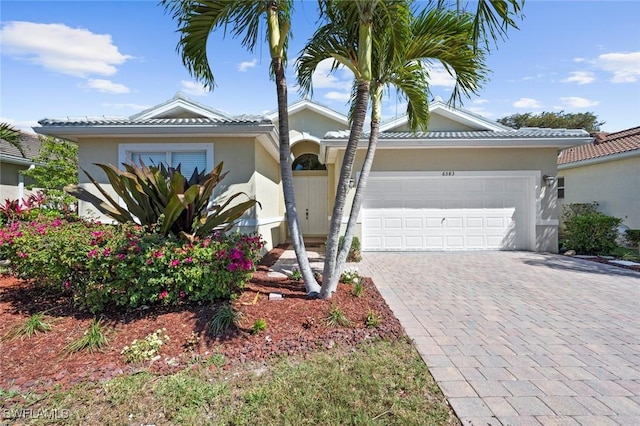 single story home featuring a tiled roof, decorative driveway, stucco siding, and an attached garage