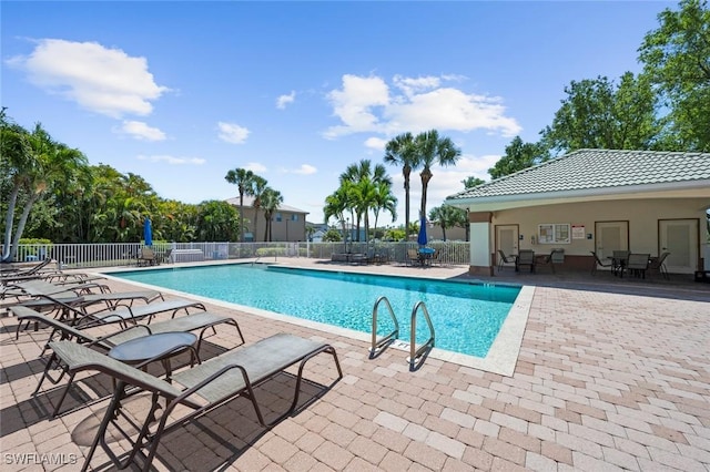 community pool with a patio area and fence