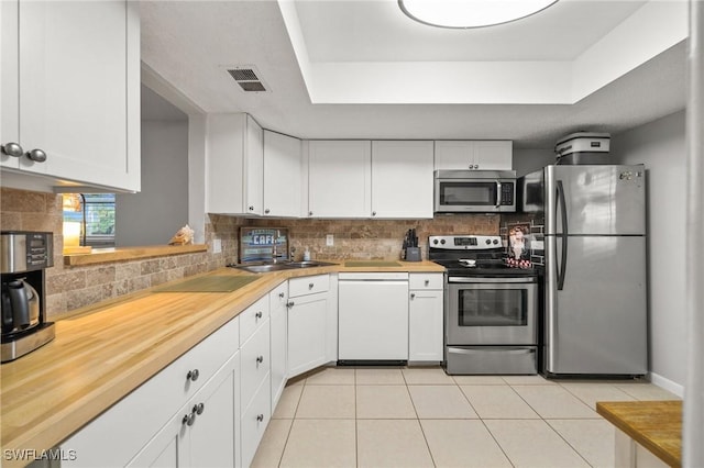 kitchen featuring stainless steel appliances, a tray ceiling, visible vents, and a sink