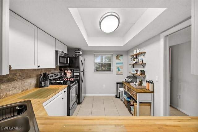 kitchen featuring butcher block countertops, white cabinets, tasteful backsplash, a sink, and stainless steel appliances