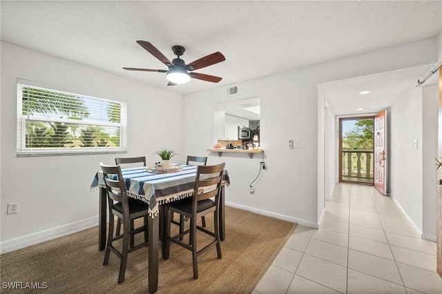 dining room featuring light tile patterned floors, baseboards, a ceiling fan, and visible vents