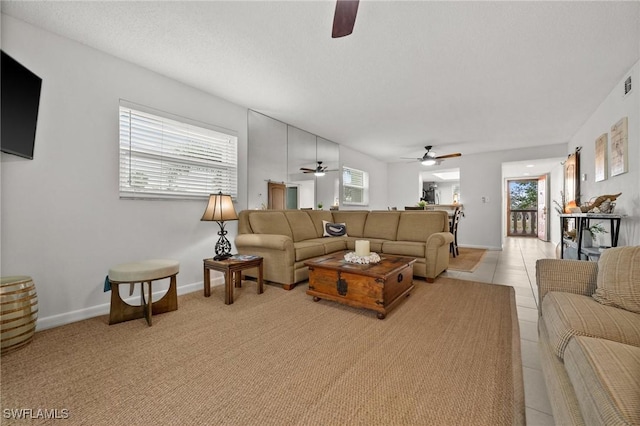 living room with baseboards, ceiling fan, and visible vents