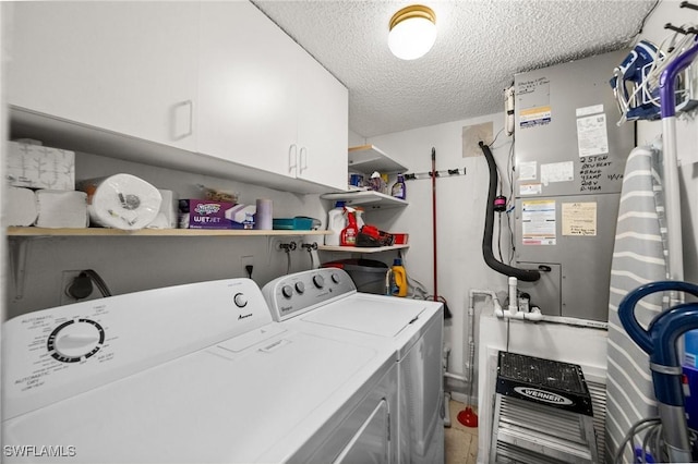 laundry room with independent washer and dryer, a textured ceiling, and cabinet space
