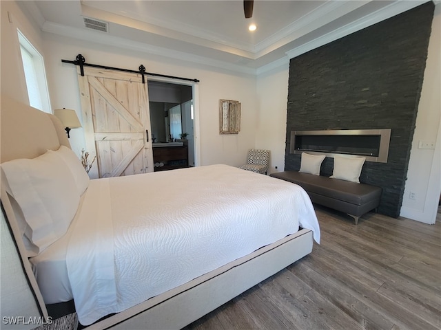 160 Coral Vine Dr, Naples, FL 34110 - bedroom featuring visible vents, crown molding, wood finished floors, a raised ceiling, and a barn door