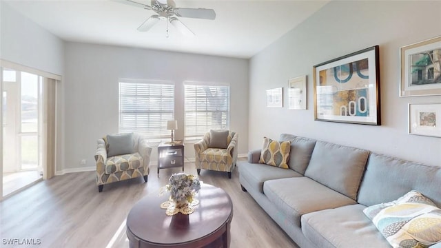 living room featuring plenty of natural light, light wood-type flooring, a ceiling fan, and baseboards