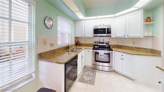 kitchen with appliances with stainless steel finishes, a sink, white cabinets, and light tile patterned floors