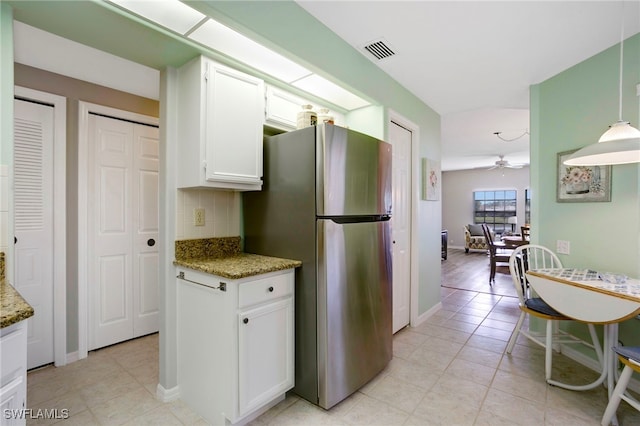 kitchen with freestanding refrigerator, tasteful backsplash, white cabinetry, light stone countertops, and ceiling fan