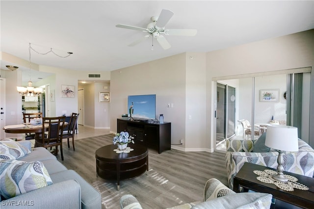 living room featuring wood finished floors, a chandelier, ceiling fan, and baseboards