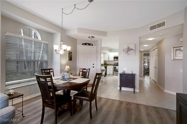 dining area featuring light wood-style flooring, baseboards, and a chandelier