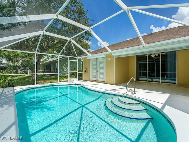 outdoor pool featuring glass enclosure and a patio