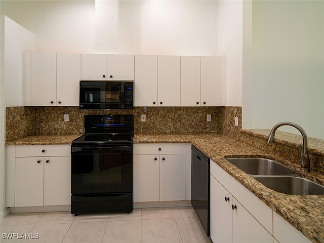 kitchen with a sink, light tile patterned flooring, stone counters, black appliances, and tasteful backsplash