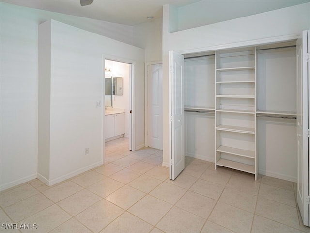 unfurnished bedroom featuring baseboards, a closet, ensuite bathroom, and light tile patterned floors