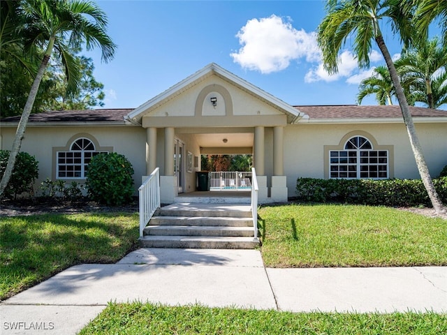 view of front facade with a porch, a front yard, a carport, and stucco siding