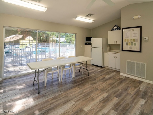 dining room featuring wood finished floors, visible vents, vaulted ceiling, and a ceiling fan
