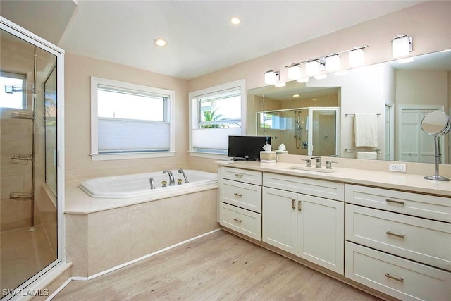 full bathroom featuring wood finished floors, recessed lighting, vanity, a stall shower, and a garden tub