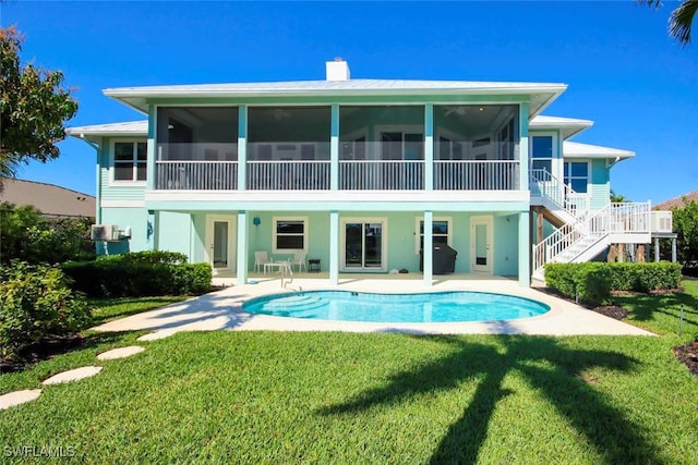 back of house featuring a sunroom, a patio, stairway, and a yard