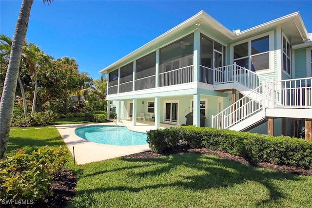 rear view of house featuring a sunroom, an outdoor pool, stairway, a yard, and a patio area