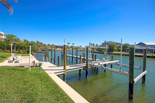 dock area with a water view, a lawn, and boat lift