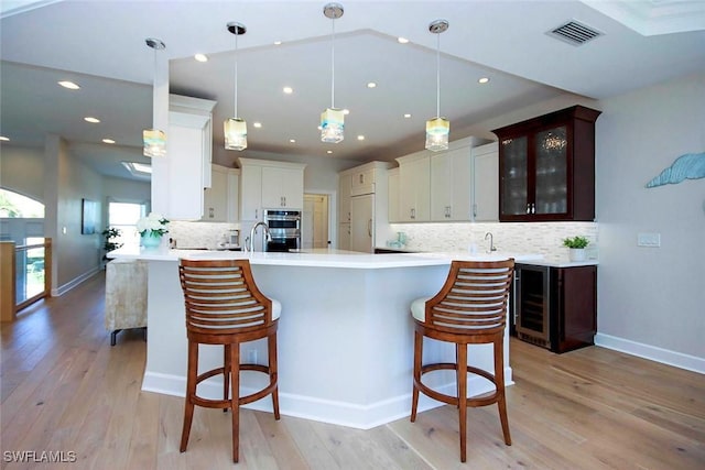 kitchen featuring light countertops, visible vents, light wood-style floors, and a breakfast bar area