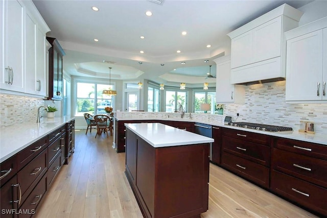 kitchen with light countertops, light wood-type flooring, white cabinets, and a raised ceiling