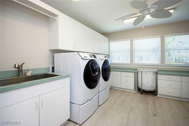 clothes washing area with washer and clothes dryer, a wealth of natural light, a sink, light wood-style floors, and cabinet space