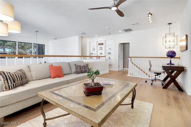 living room featuring light wood-type flooring, recessed lighting, a ceiling fan, visible vents, and built in shelves