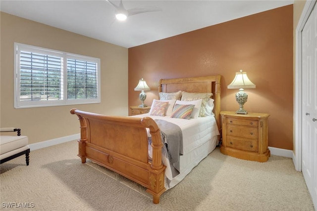 bedroom with a closet, light colored carpet, and baseboards