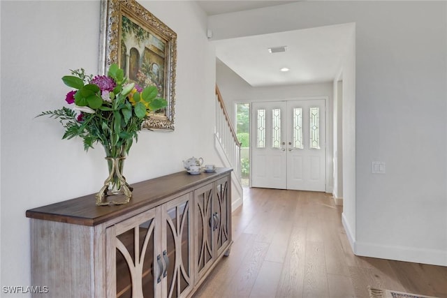 entrance foyer featuring baseboards, wood-type flooring, visible vents, and stairs