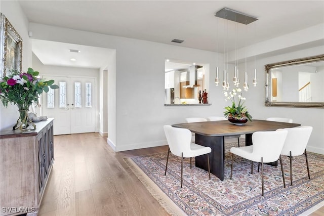 dining room featuring visible vents, baseboards, and wood finished floors
