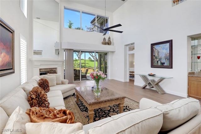 living room with ceiling fan, baseboards, wood finished floors, and a fireplace