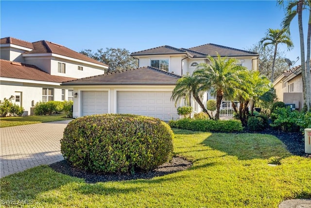 view of front facade with stucco siding, a front lawn, a tile roof, a garage, and driveway
