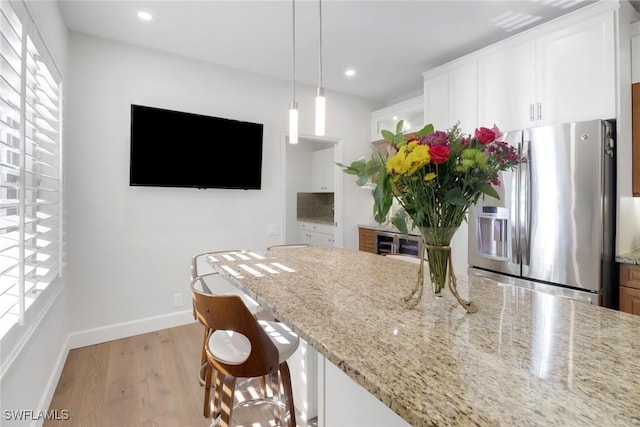 kitchen featuring baseboards, stainless steel refrigerator with ice dispenser, white cabinetry, light wood-style flooring, and light stone counters