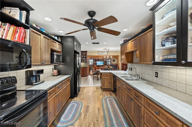 kitchen featuring a sink, brown cabinets, black appliances, light wood-style floors, and ceiling fan