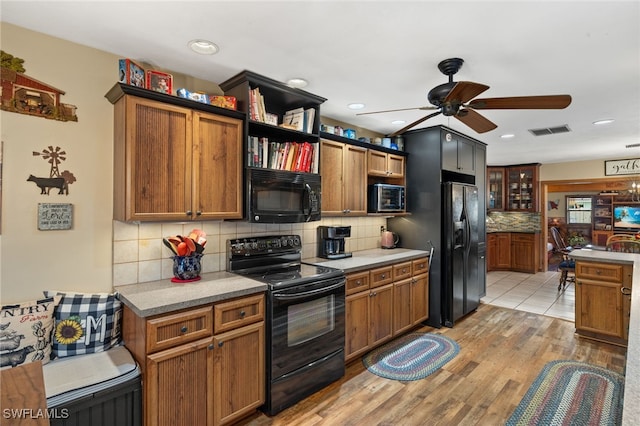 kitchen featuring backsplash, light wood-style flooring, visible vents, black appliances, and ceiling fan
