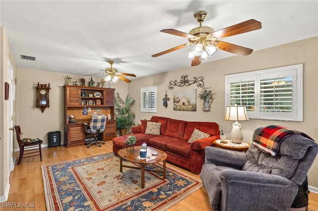 living area with a ceiling fan, light wood finished floors, and visible vents